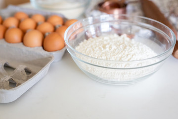 Close up of bowl of flowers, eggs and cake ingredients in background