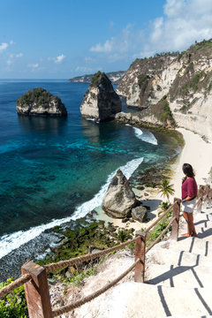 Woman exploring a tropical sand beach surrounded by cliffs