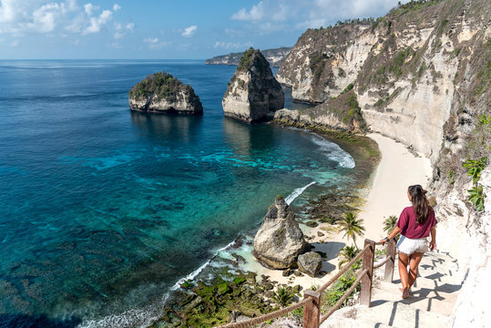 Woman exploring a tropical sand beach surrounded by cliffs
