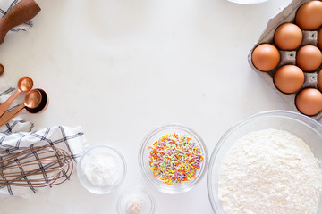 cake ingredients on white background, rainbow sprinkles in bowl