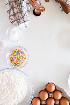 cake ingredients on white background, rainbow sprinkles in bowl