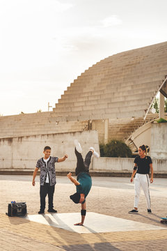 Young male performing a dance pose in the park at sunset surrounded by mixed race group of friends