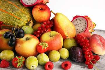 Tropical fruits background, many colorful ripe fruits with strawberries, grapes and cherries on wooden background