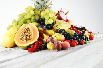 Tropical fruits background, many colorful ripe fruits with strawberries, grapes and cherries on wooden background