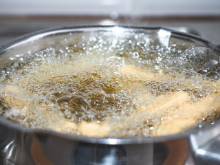 Close up frozen pastry frying in a pot with hot oil.