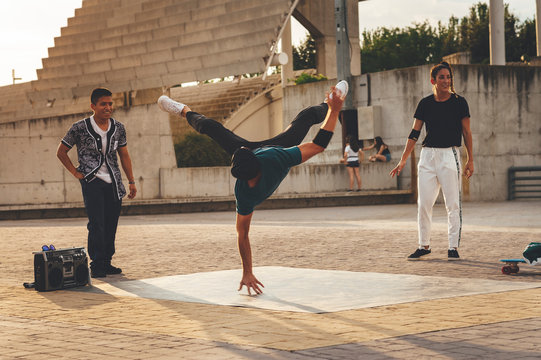 Young male performing a dance pose in the park surrounded by mixed race group of friends
