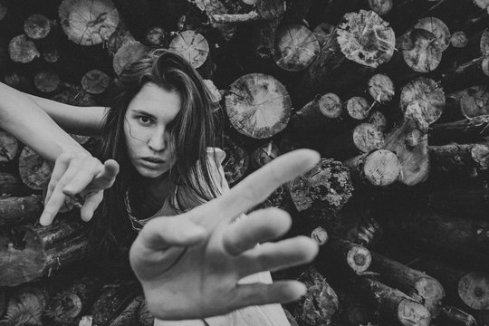 A girl is dancing against a woodpile.