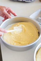 woman spreading batter with spatula in cake pan