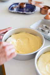 woman spreading batter with spatula in cake pan