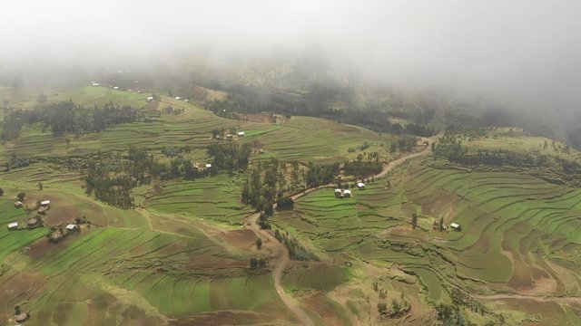 Flying through mist over small village community and rural unpaved road in mountains of North Ethiopia