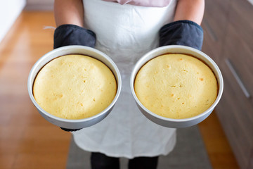 woman holding two baked cakes in metal pans
