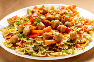 Farfalle pasta with sausages, vegetables and tomato sauce