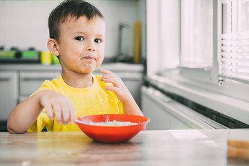 A child in a yellow t-shirt in the kitchen eating Russian national dish Okroshka