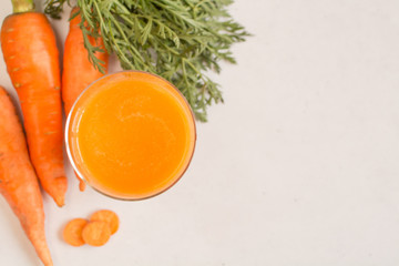 Glass of carrot juice and carrots on a white background. Copy space. Top view.