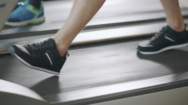 Closeup feet walking on treadmill in fitness gym slowly.