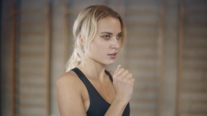 Portrait of motivated woman running on treadmill machine in sport club.