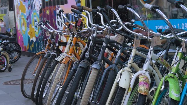 Many bicycles stand in a row in street parking. Ecologically clean transport. View of the wheels