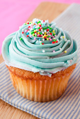 Blue cupcake with frosting and sprinkles