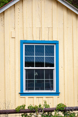 Old house with yellow wall with blue window trim