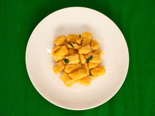 Pumpkin gnocchi with sage and butter on a white plate