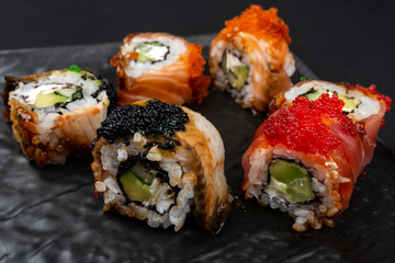 Sushi roll Philadelphia with salmon, smoked eel, avocado, cream cheese on black background. Sushi menu. Japanese food.