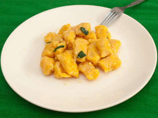 Pumpkin gnocchi with sage and butter on a white plate