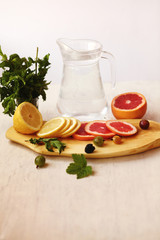 lemonade in pitcher, sliced lemon and grapefruit ,fresh berries and a bundle of fresh mint on a white background /a healthy lifestyle