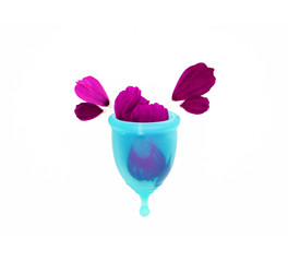 a woman personal hygiene item for a period, a blue menstrual cup filled with flower petals, like a metaphor of a drop of blood splashing overflowed on a white background - obrazy, fototapety, plakaty
