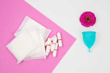 female personal hygiene products isolated on a white background blue menstrual cup and swabs pads on a pink background as a choice eco-friendly zero waste reusable product for a period of time.