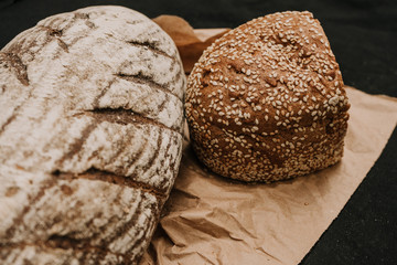 Fresh bread on paper on wooden black background