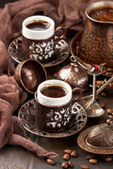 Hot coffee in Turkish copper  pot, traditional mugs  and coffee beens