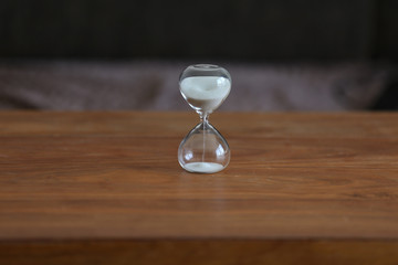 Time. Glass hourglass stands on the table.