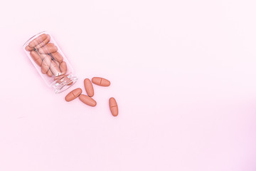 Flat lay overhead of big pink pills in glass jar on light pink background with copy space for your design. Health care concept. Minimalism style template for medical blog , social media.