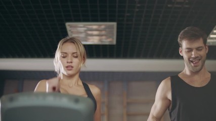 Sexy sportsman flirting serious lady on running machine.