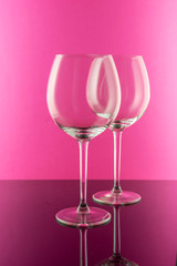 Reflection at the Empty Wine Glasses on pink background. Wine concept. 
