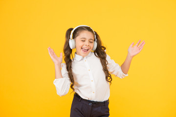 The song clicks with her mood. Adorable little girl singing a song on yellow background. Cute small...