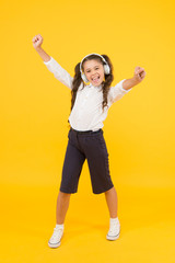 Fototapeta na wymiar Because Im happy. Happy small girl listening to music on yellow background. Little child enjoying song playing in headphones with smile on happy face. Happy music for kids