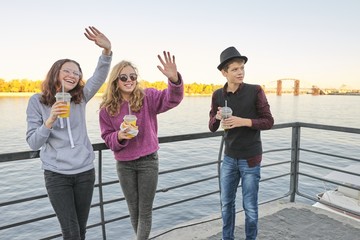 Teenagers boy and two girls with street food talking outdoor