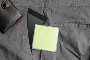 Smartphone device inside trousers front pocket with wallet and note paper