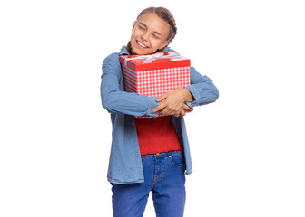 Portrait of dreamy Teen girl holding red gift box, isolated on white background. Happy child hugs her birthday or christmas present. Cute caucasian young teenager smiling with eyes closed.