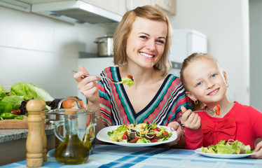 Mom and daughter eating vegetable salad