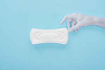top view of white paper hand and cotton sanitary towel on blue background