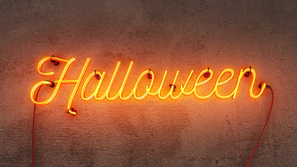 Neon sign that says the word Halloween in bright yellow / orange colours, on a grunge concrete wall background.