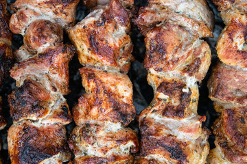 Frying pork on a skewer over a brazier. Turning meat over coals. Appetizing shish kebab.