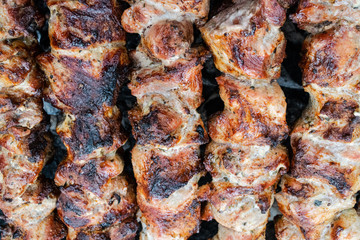 Frying pork on a skewer over a brazier. Turning meat over coals. Appetizing shish kebab.