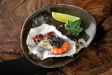 Fresh oysters with black sturgeon caviar and shrimp in ice, with lime in a luxurious serve in a...