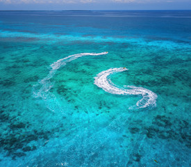 Aerial view of floating water scooter in clear blue water at sunny day in summer. Holiday in Zanzibar, Africa. Top view of jet ski in motion. Tropical seascape with moving motorboat. Extreme. Boats