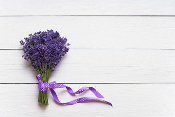 Bunch of fresh lavender decorated with ribbon on white wooden background. Top view, copy space.