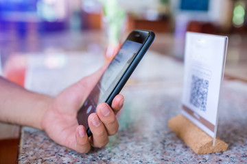 Closeup of a hand holding phone and scanning qr code. Man hand paying with qr code. Customer hand making payment through smart phone and scan code. Selective focus