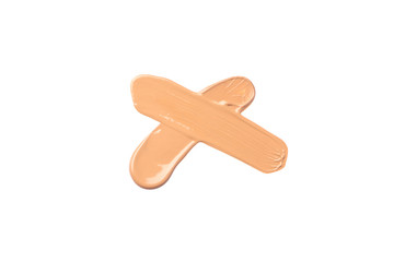 Bright beige smear of foundationin the form of a cross isolated on a white background.